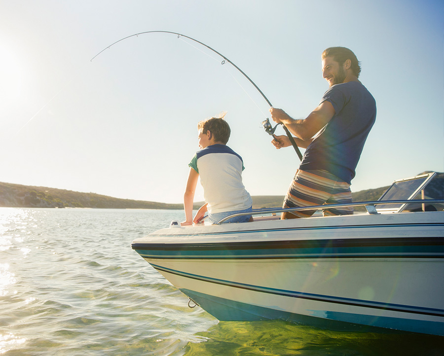 A father and son fishing off a boat